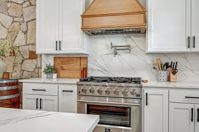 a kitchen with stainless steel appliances granite countertop a stove and a white cabinet