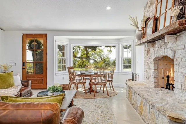 a living room with furniture a fireplace and large windows