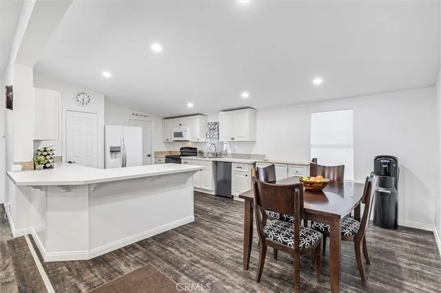 a kitchen with a dining table chairs and wooden floor
