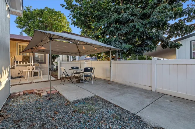 a view of a patio with table and chairs under an umbrella with a barbeque