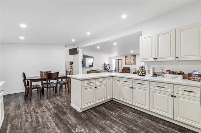 a kitchen with white cabinets sink and chairs
