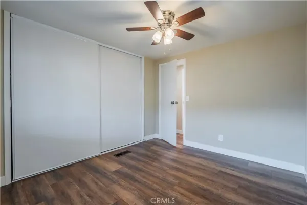 an empty room with wooden floor and fan