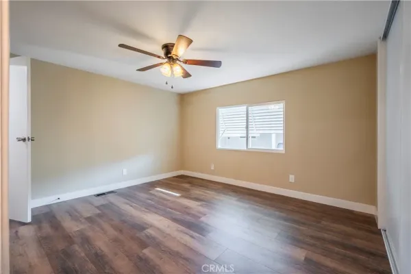 an empty room with wooden floor fan and windows