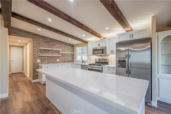 a large kitchen with stainless steel appliances a large counter top a stove and a refrigerator