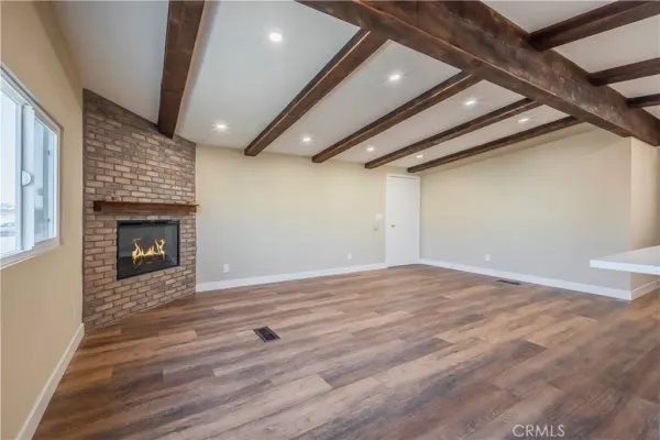 a view of an empty room with wooden floor and a fireplace