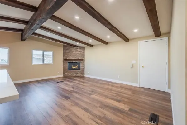 an empty room with wooden floor fireplace and windows