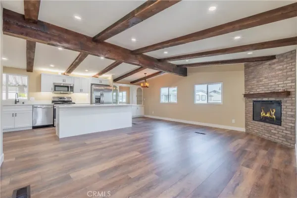 a large white kitchen with kitchen island a stove a sink dishwasher and a fireplace with wooden floor