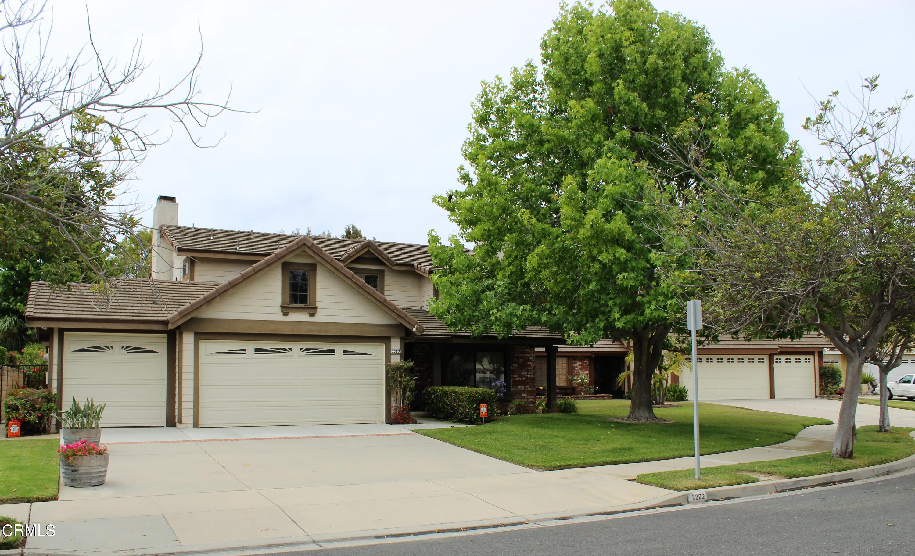 a front view of a house with a garden and trees