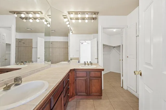 a spacious bathroom with a granite countertop sink a mirror and a shower