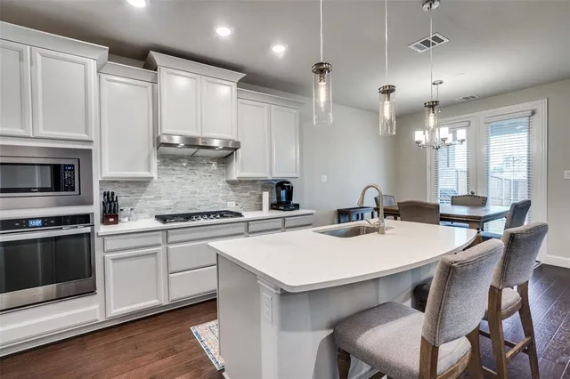 a kitchen with granite countertop a stove a sink a kitchen island with a refrigerator and cabinets