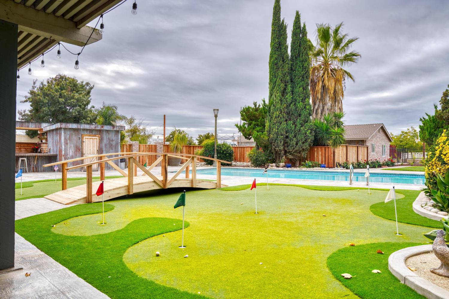 13791 Castle Road Manteca, CA 95336 - Photo 41 of 96 view of community with an area to practice putting, a fenced backyard, a wooden bridge, and a pool