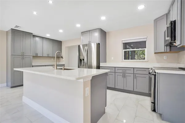 a kitchen with kitchen island granite countertop a sink stainless steel appliances and cabinets