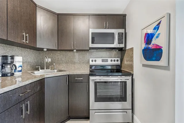 a kitchen with stainless steel appliances granite countertop a stove microwave and sink
