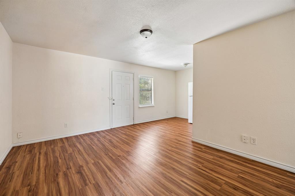 6221 Pine Street Rowlett, TX 75089 - Photo 3 of 12 Open concept living space featuring wood-finish flooring, neutral wall tones, and a bright window