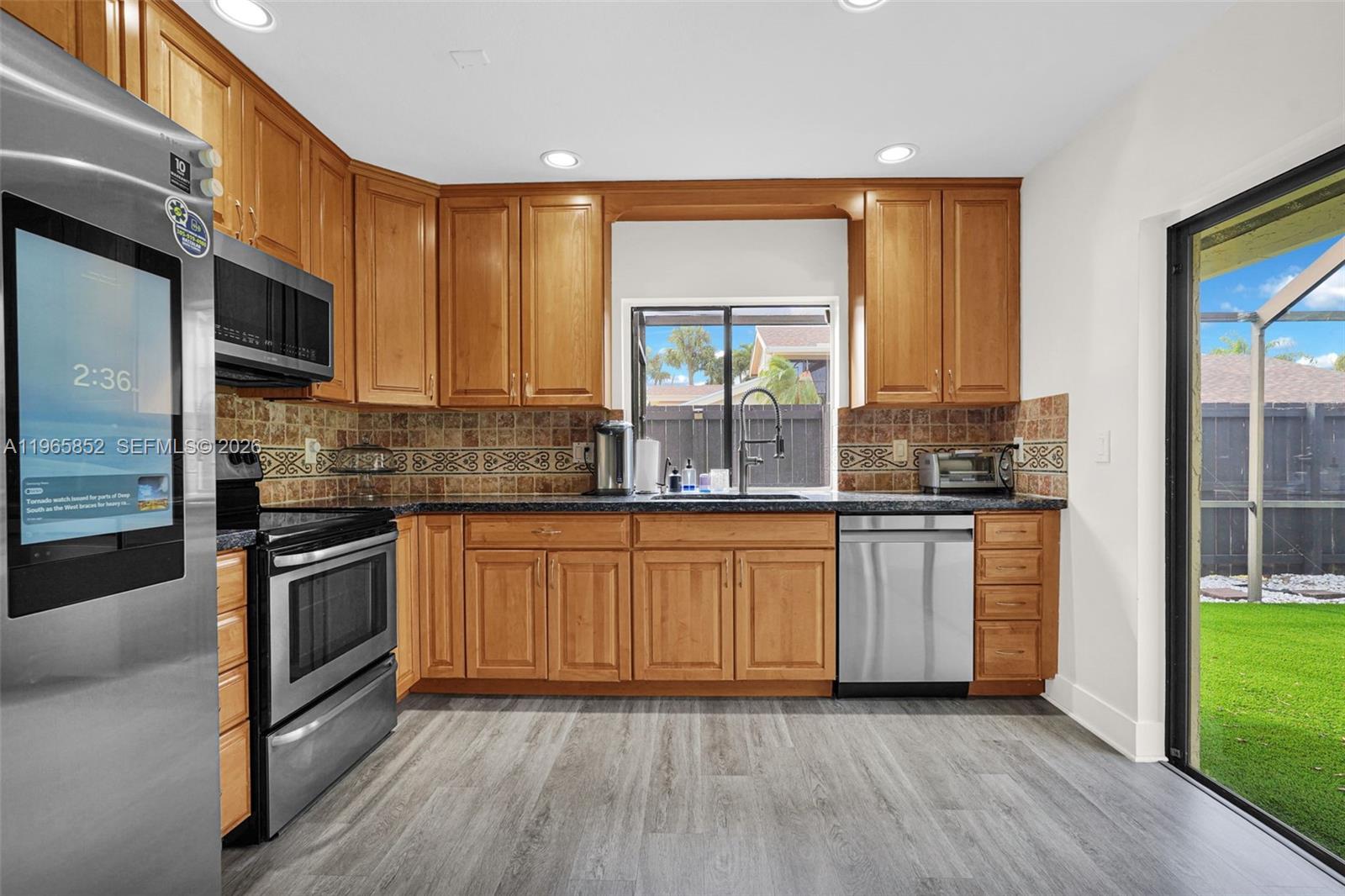 7635 Sierra Terrace West Boca Raton, FL 33433 - Photo 17 of 53 a kitchen with granite countertop wooden floors stainless steel appliances a sink and a window