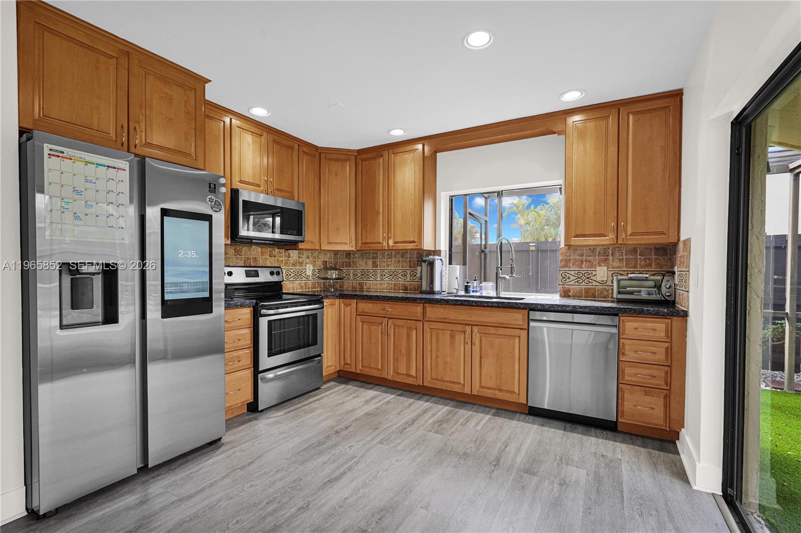 7635 Sierra Terrace West Boca Raton, FL 33433 - Photo 21 of 53 a kitchen with stainless steel appliances granite countertop a refrigerator a sink dishwasher a kitchen island with cabinets and wooden floor