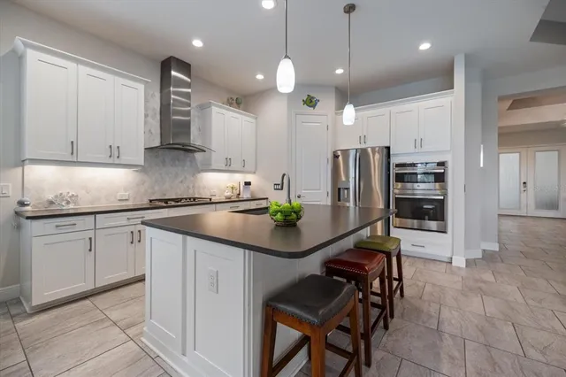 a kitchen with stainless steel appliances granite countertop a sink a stove a refrigerator and island with wooden floor