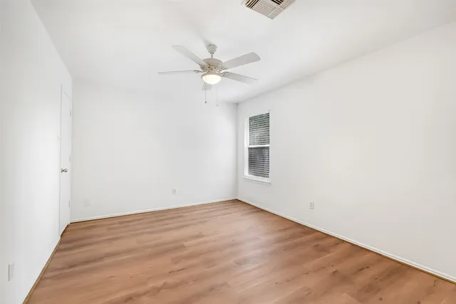 an empty room with a window and ceiling fan