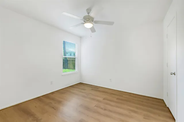 an empty room with a window and a fan