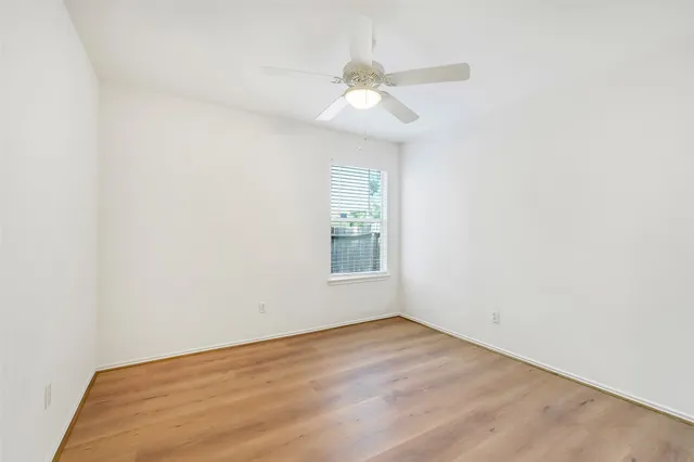 an empty room with a window and a fan