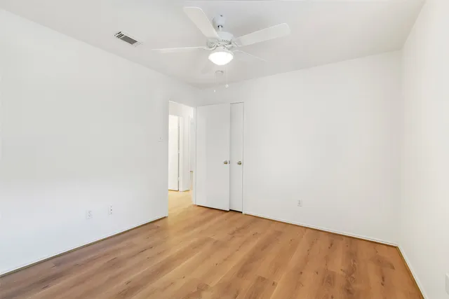 an empty room with a ceiling fan and wooden floor