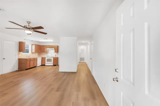 a view of a kitchen with a sink cabinet a ceiling fan and wooden floor
