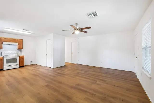 a view of an empty room with a ceiling fan and window