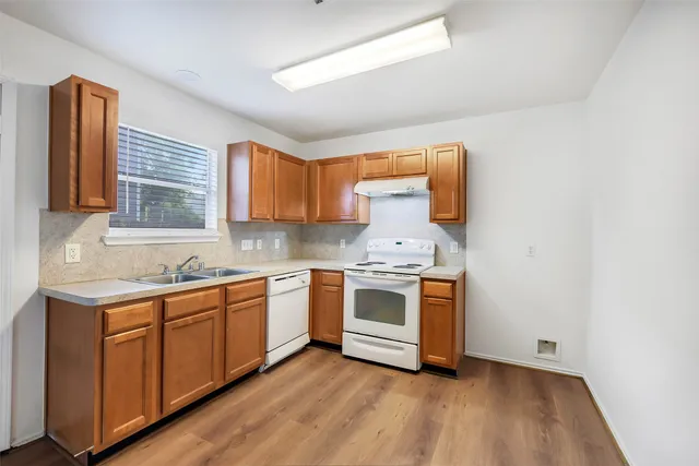 a kitchen with stainless steel appliances granite countertop a sink and cabinets with wooden floor