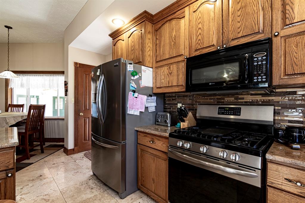 9215 Ridge Road New Port Richey, FL 34654 - Photo 31 of 71 a kitchen with stainless steel appliances granite countertop a stove refrigerator and microwave