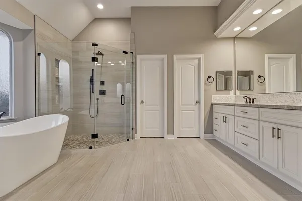 a spacious bathroom with a double vanity sink a large mirror a shower and bathtub