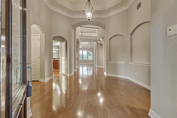 a view of a hallway with wooden floor and chandelier