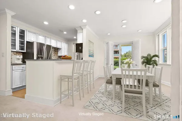 a kitchen with stainless steel appliances kitchen island granite countertop a refrigerator and a dining table