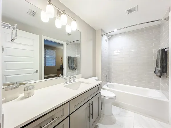 a bathroom with a sink a toilet a mirror and shower