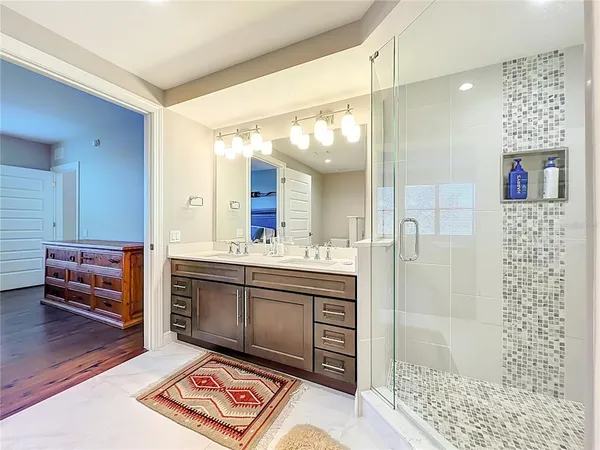 a spacious bathroom with a double vanity sink a mirror and a shower