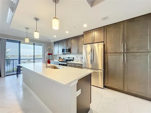 a large kitchen with stainless steel appliances a refrigerator a stove a sink a center island and a refrigerator