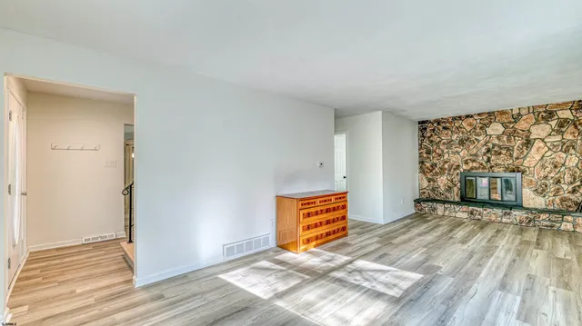 an empty room with wooden floor fireplace and windows