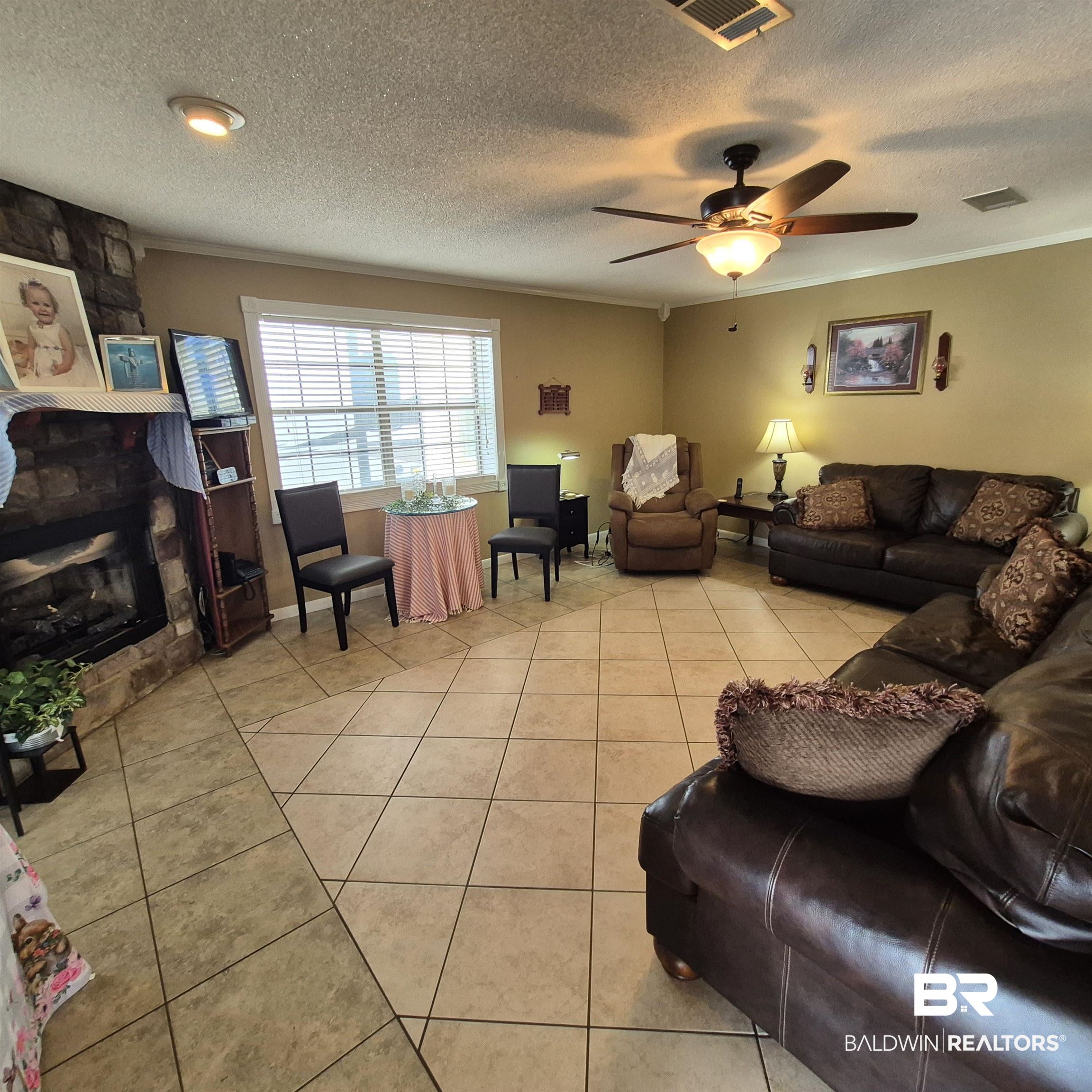 26635 Highway 41 Range, AL 36473 - Photo 9 of 74 Living area with light tile patterned flooring, a fireplace, a ceiling fan, a textured ceiling, and crown molding