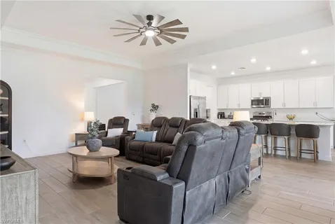 a living room with couches a fireplace and kitchen view with wooden floor