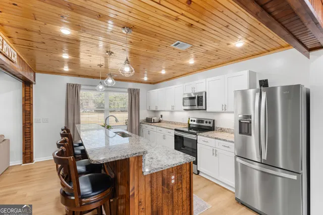 a kitchen with kitchen island a counter top space cabinets stainless steel appliances and a large window