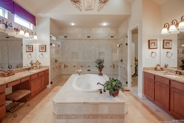 a large white bathroom with a tub sink a mirror and shower