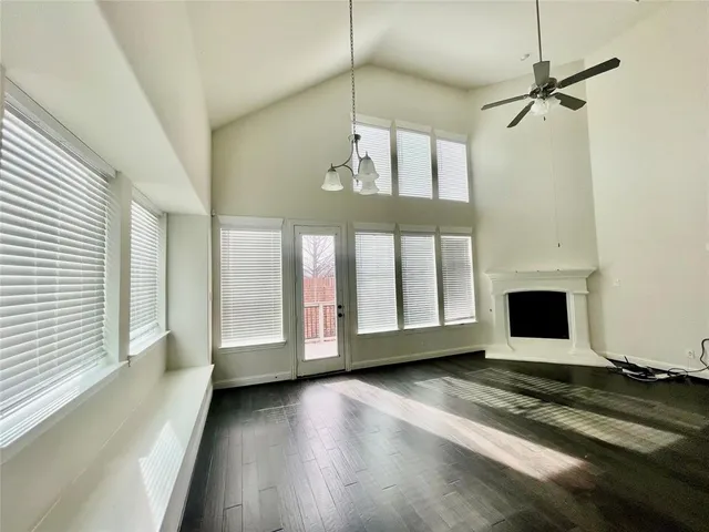 a view of a livingroom with wooden floor a ceiling fan and window