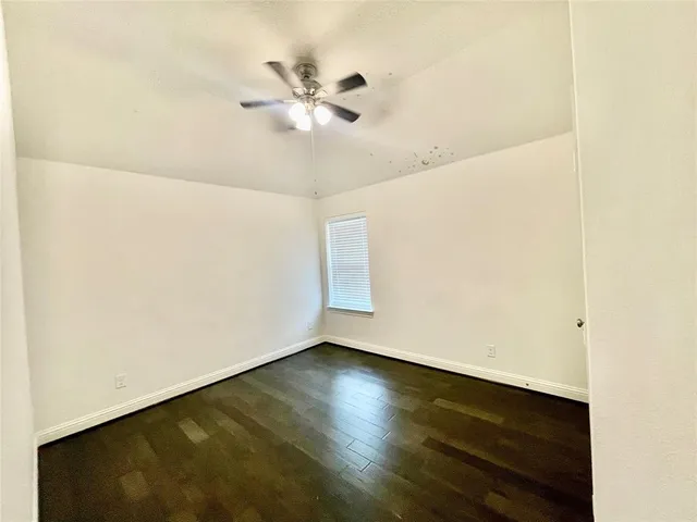 an empty room with wooden floor and fan