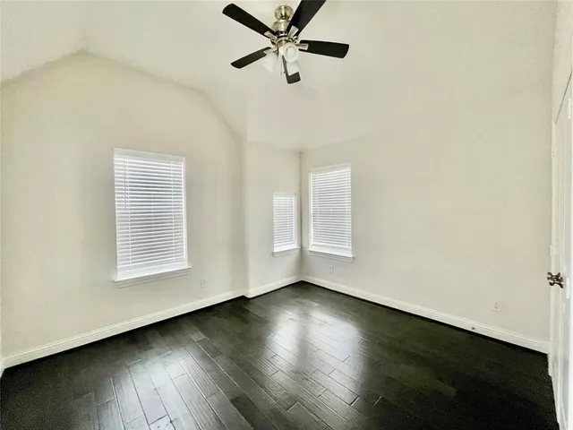 an empty room with wooden floor closet fan and windows