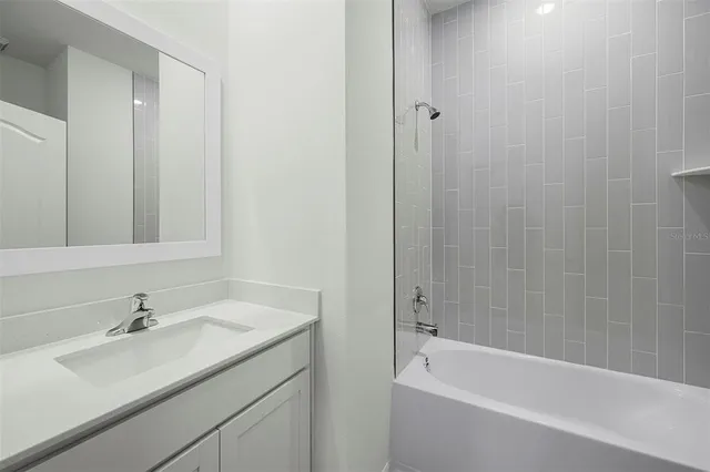 a bathroom with a tub sink vanity granite and a mirror