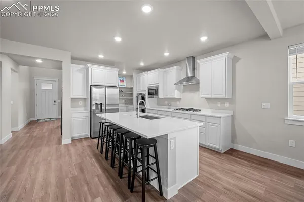 a kitchen with kitchen island wooden floors appliances and white cabinets