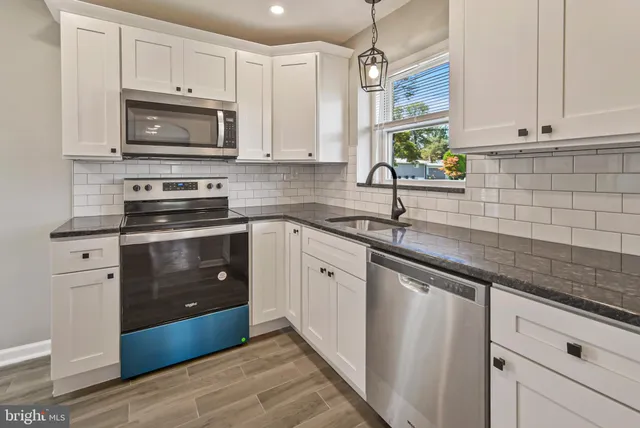 a kitchen with granite countertop white cabinets white stainless steel appliances with a sink and dishwasher