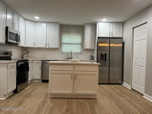 a kitchen with white cabinets stainless steel appliances and wooden floor