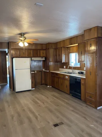 a kitchen with stainless steel appliances a refrigerator a sink cabinets and wooden floor