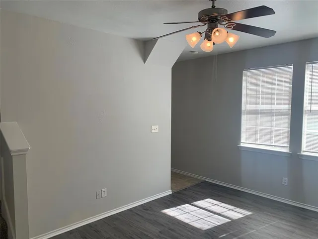 an empty room with wooden floor chandelier fan and window