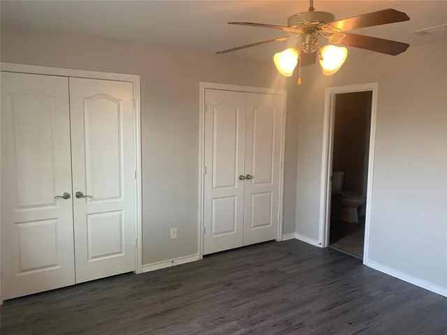 an empty room with wooden floor closet and windows